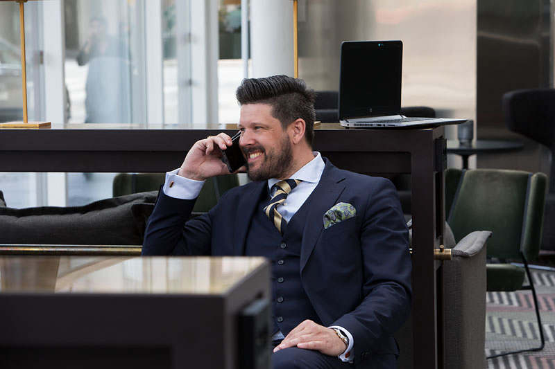 Henric sitter och pratar i telefon och ler. Henric är specialist på avtalsrätt och arbetsrätt.